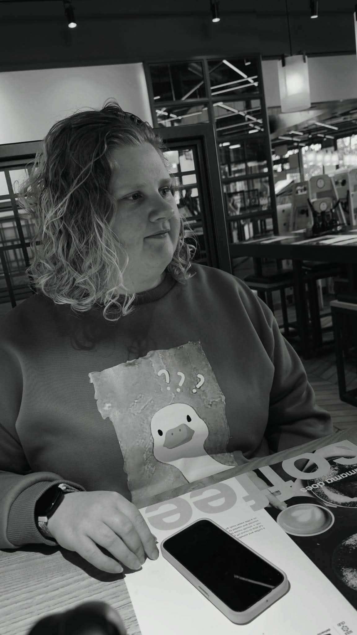 Black-and-white portrait of Katie Hoare seated in a café.